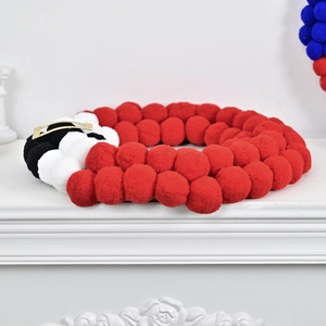 Festive Santa-themed Christmas ball garland with red white black pom-poms and gold buckle