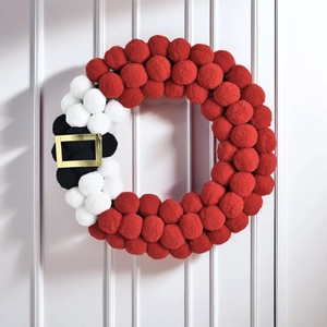 Christmas wreath with red, white and black pom-poms featuring a Santa Claus belt buckle design