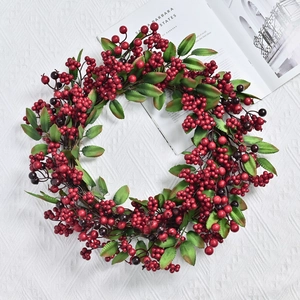 Round artificial Christmas wreath with vibrant red winter berries and green leaf foliage