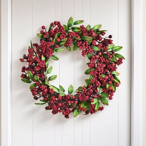 Artificial Christmas wreath with red winter berries and green leaves on white door