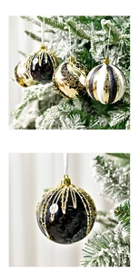 Dettagli di lussuose palline di Natale nero e oro con motivi a rilievo su un ramo di albero