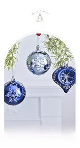 Blue and silver hand-painted Christmas ornaments hanging on a pine tree with white snowflakes