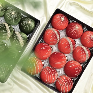Macro shot of red and green velvet Christmas balls with gold glitter in a black gift box