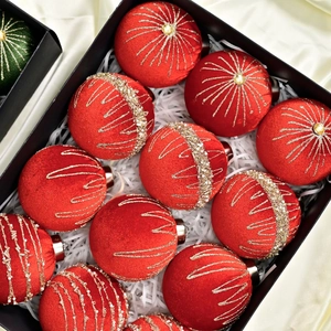 Macro view of velvet red Christmas ball with gold patterns and pearls in gift box