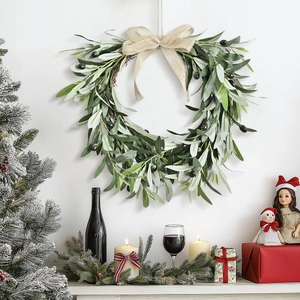 Christmas olive leaf wreath with burlap bow hanging on wall above fireplace decor