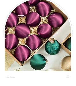Close-up of assorted satin velvet Christmas ornaments in a premium gift box with straw