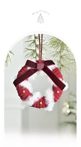 Detail of red knit Christmas wreath with white fur trim and velvet bow on pine branch