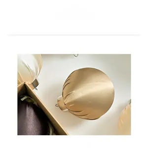 Close-up of champagne gold satin Christmas ball with pleated texture and silver cap