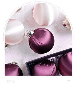 Close-up of velvet and satin Christmas balls with silver hooks on white plush background
