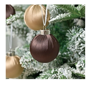 Detail of satin chocolate and champagne Christmas balls hanging on snow-covered pine branches