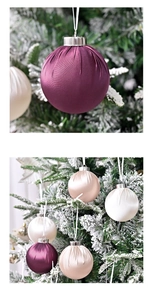 Detail showing pleated satin Christmas ornaments in purple and champagne on a snowy tree