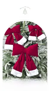 Detail of red velvet Christmas bows with white faux fur trim hanging on snowy tree branches