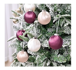 Close-up of luxury satin Christmas balls in purple and champagne on a snowy tree
