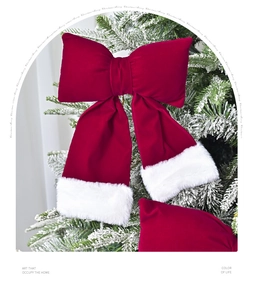 Detail view of large red velvet Christmas bow with white plush trim on tree branch