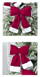 Close-up of a large red velvet Christmas bow with white faux fur trim on a snowy tree