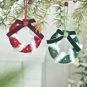 Red and green knitted Christmas mini wreaths with velvet bows on tree branches