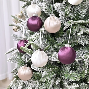 Luxury satin Christmas ornament balls set in velvet textures on a snow-covered pine tree