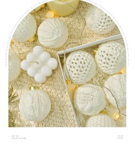 Gestrickte Weihnachtskugeln mit Zopfmustern in einer Geschenkbox mit Festbeleuchtung