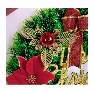 Close-up of red velvet poinsettia and glittery Merry Christmas sign on a festive wreath