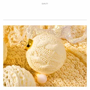Close-up of white cable knit Christmas ball with golden metal hook and LED string lights