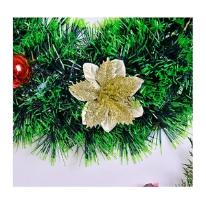 Close-up of Christmas garland with a gold glitter poinsettia flower and red shiny ornament ball