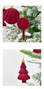 Detail of red flocked Christmas ornaments with velvet texture hanging on snowy pine branches