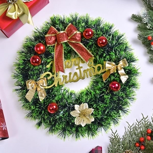 Christmas pine needle wreath with red bow, golden Merry Christmas sign and ornaments