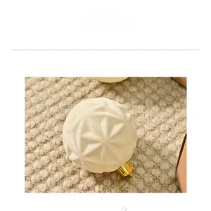 Close-up of cream Christmas ball with star texture, golden cap and cozy knit background