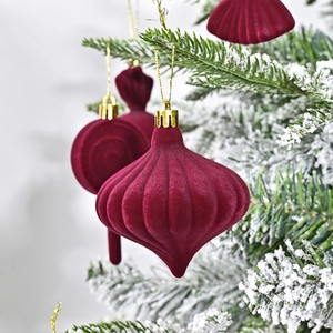 Burgundy velvet Christmas ball ornaments with textured patterns on snowy pine tree branch