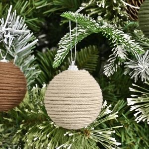 Handcrafted cream cotton rope Christmas ball ornament hanging on a snowy tree branch