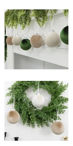 Detailed flocking velvet Christmas balls hanging on pine needles with a white fireplace background