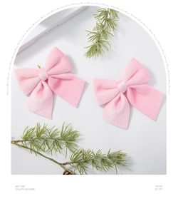 Detail of pink velvet Christmas bows with gold bead center on festive pine branches