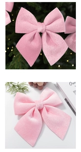 Pink velvet Christmas bow decoration hanging on tree with soft warm holiday lighting