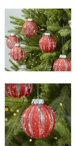 Close-up of red glitter Christmas ornaments with snow patterns hanging on a festive tree