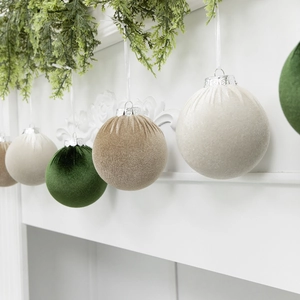 8cm flocked velvet Christmas balls in white and green hanging on a decorated mantel