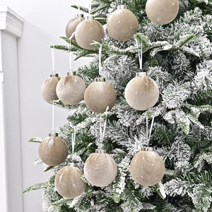 Set of 12 champagne velvet Christmas balls with silver star patterns on a snowy tree