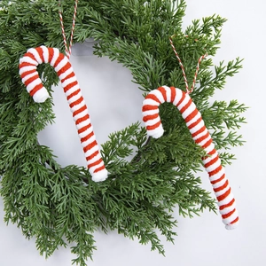 Plush red and white striped Christmas candy cane ornaments hanging on a green festive wreath