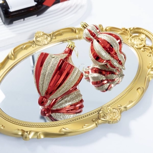 Boules de Noël à rayures rouges et dorées en forme d'oignon et de larme sur un miroir