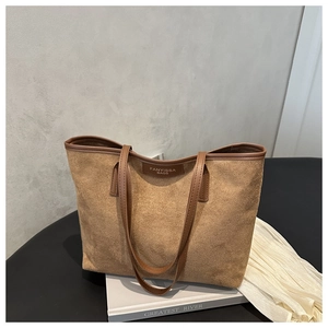 Dettaglio macro della borsa tote vintage in pelle scamosciata marrone con manico in pelle e logo