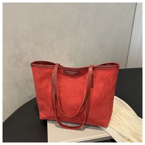 Dettaglio della borsa tote in pelle scamosciata rossa con profili in pelle e logo patch