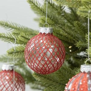 DIY transparent Christmas ornament ball with red glitter diamond pattern on green tree branch