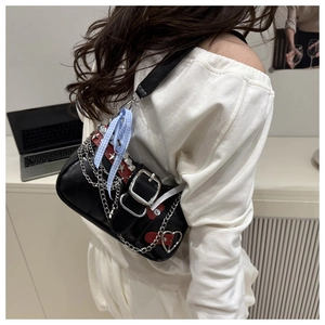 Detail of black Y2K shoulder bag with silver chain, star rivets and bow accessory