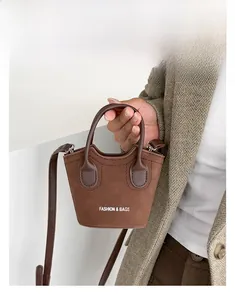 Dettaglio della borsa a secchiello in camoscio marrone con manico e logo stampato