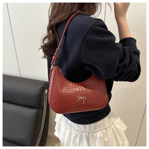 Détail du sac croissant rouge gaufré crocodile avec nœud métallique argenté sur bandoulière