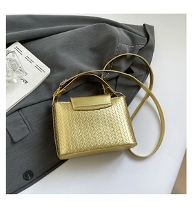 Detailed view of gold woven texture and handle on a minimalist crossbody square bag