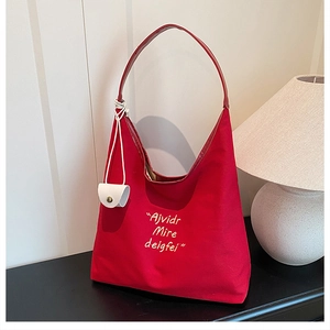 Detail of red canvas tote with white embroidery and leather button charm attachment