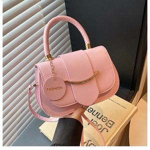 Detailed shot of pink leather handbag with gold metal bar and delicate shoulder strap
