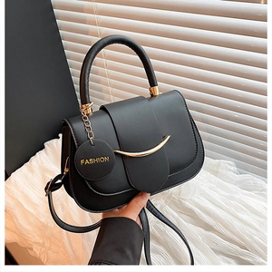 Macro detail of black leather shoulder bag featuring a gold metal buckle and FASHION tag