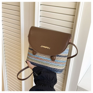 Detail of a colorful striped straw bucket bag with brown leather flap and gold logo