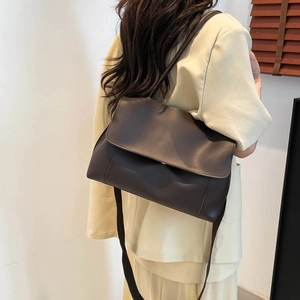 Minimalist dark brown oversized tote bag in matte leather shown on shoulder for daily commute